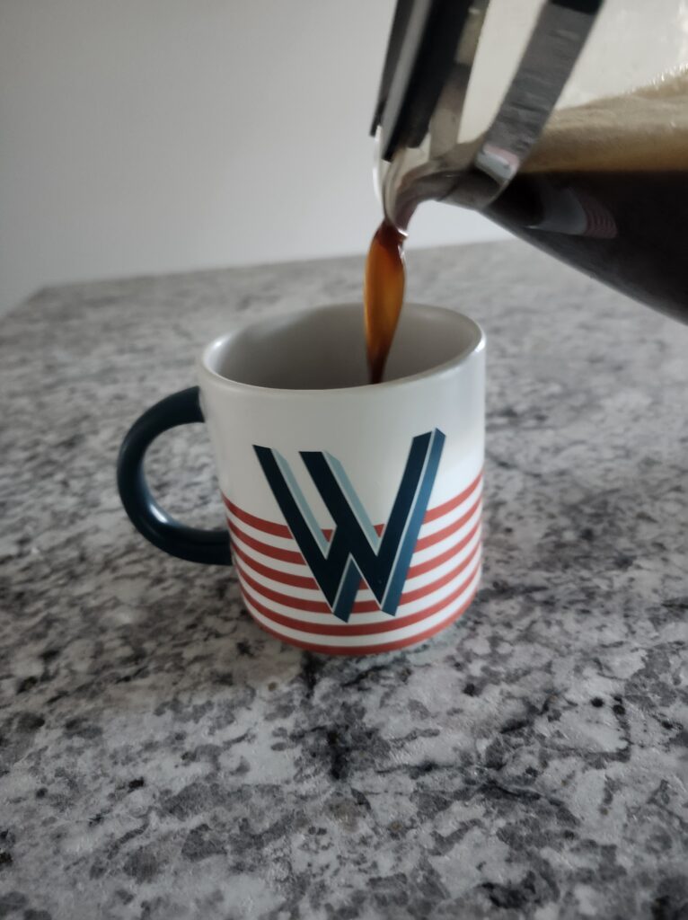 Coffee pot with coffee pouring coffee into a coffee cup