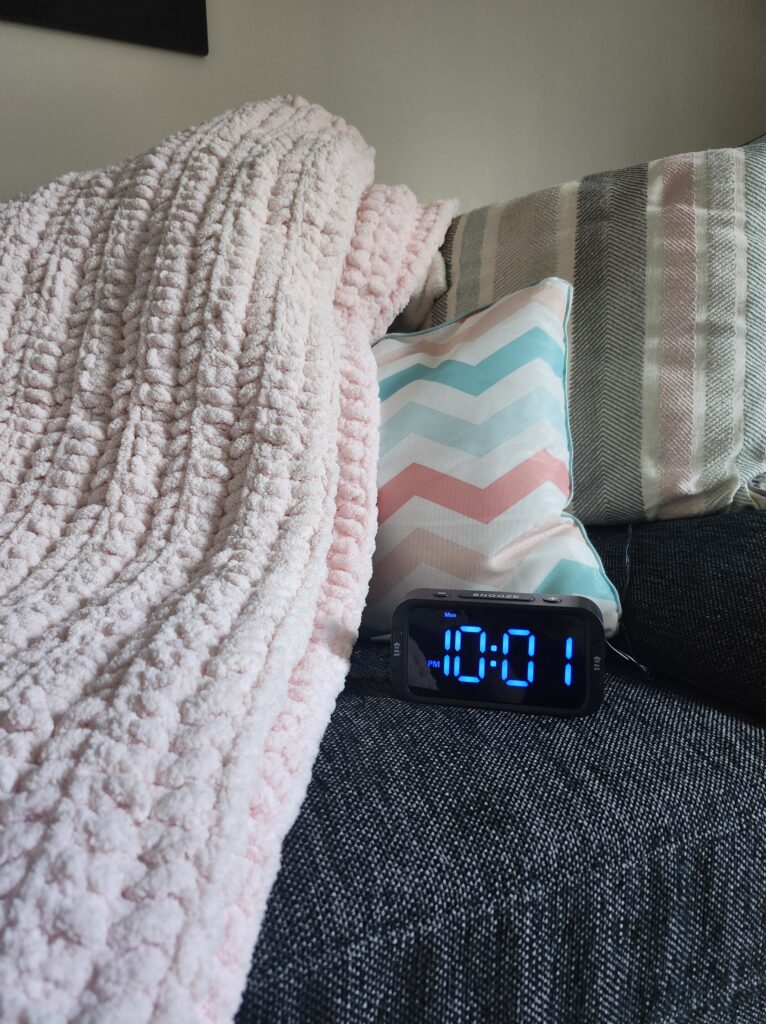 Cozy bed with pillo and blanket and alarm clock