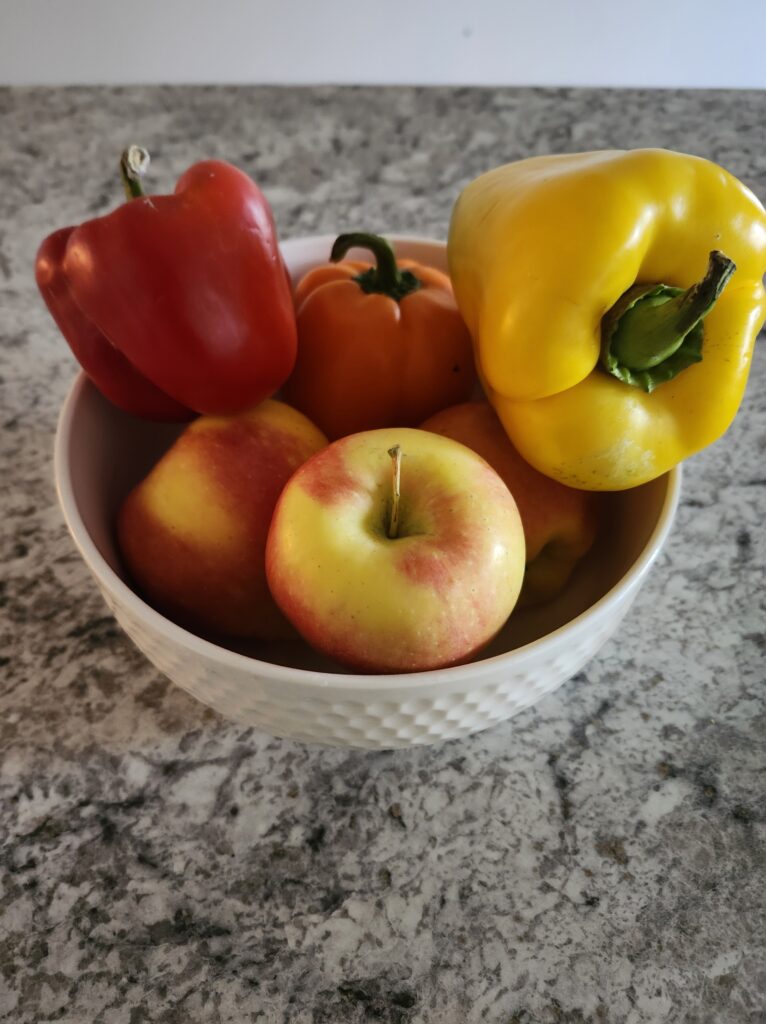 Bowl of frest apples and peppers sitting on the counter