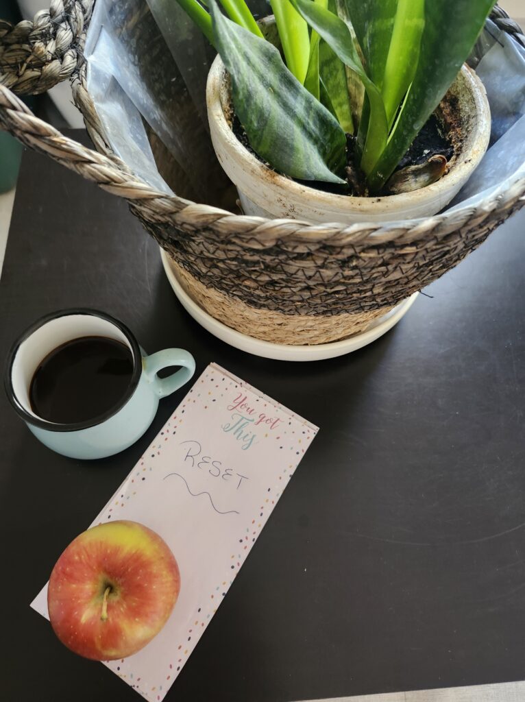 Plant, coffee, apple and notepad with reset on it to prepare for the week