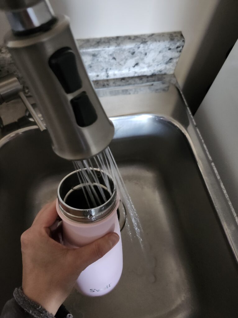 Pouring water into water bottle to keep those small hydration habits going.