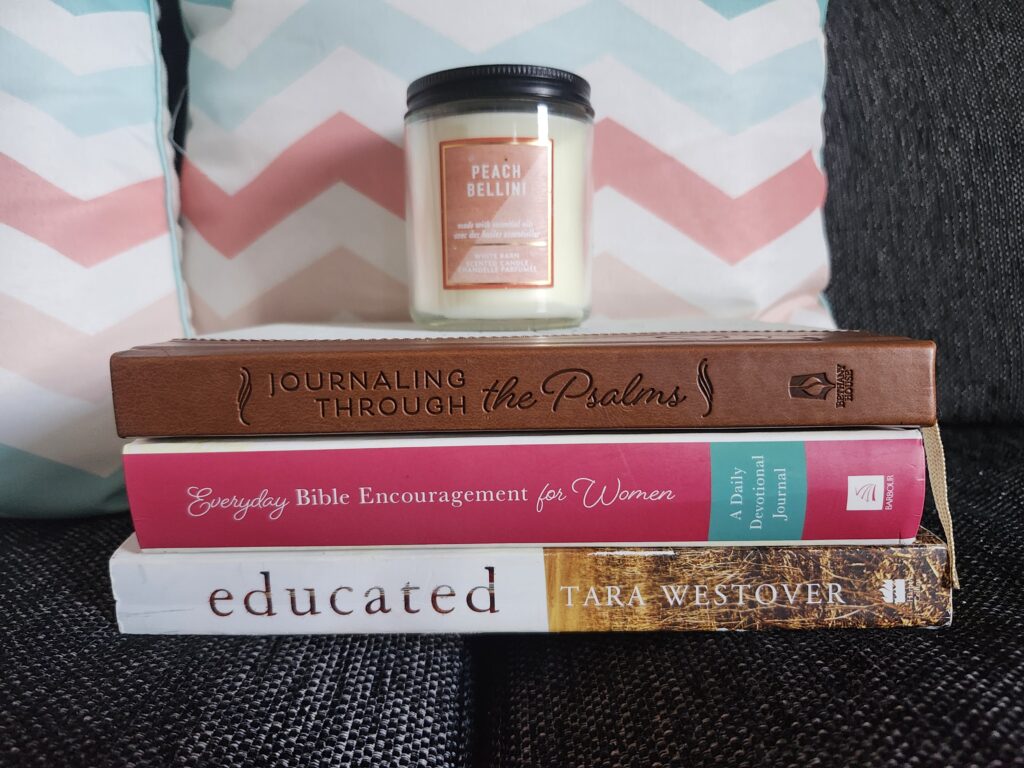 Stack of books on couch with a candle