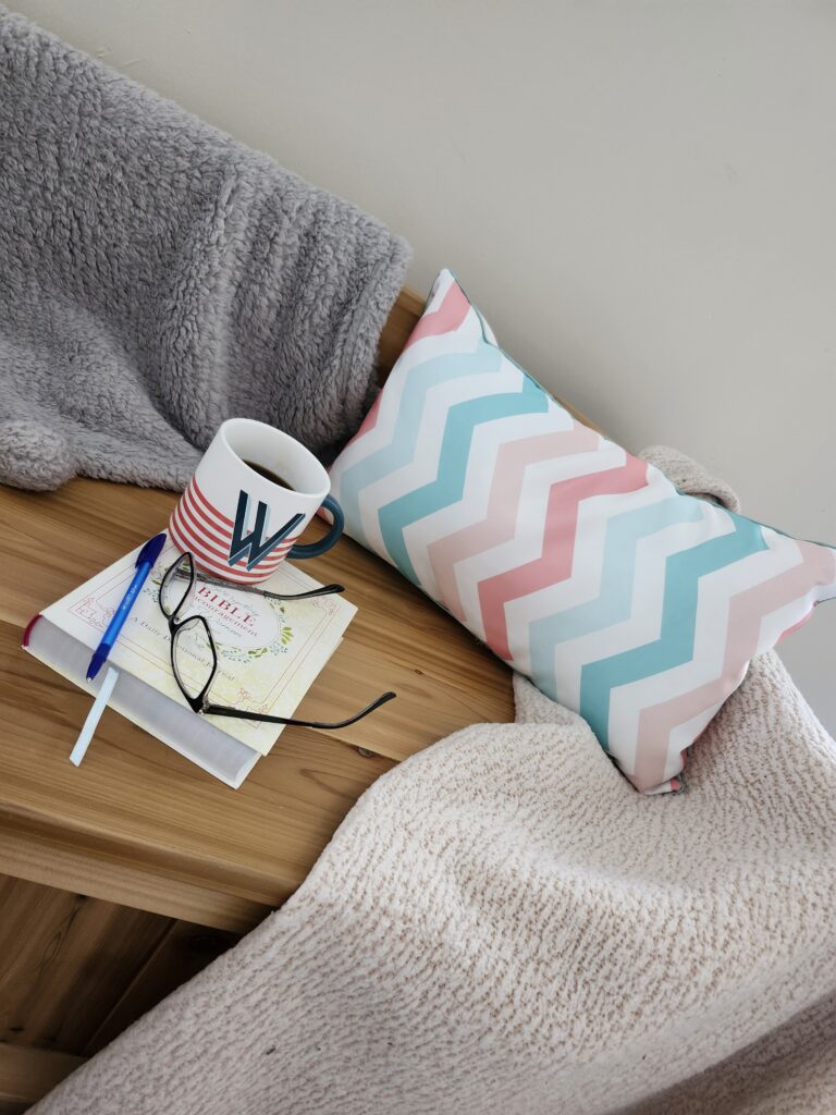 Cozy corner with a pillow, journal and pen, coffee  and glasses and a blanket