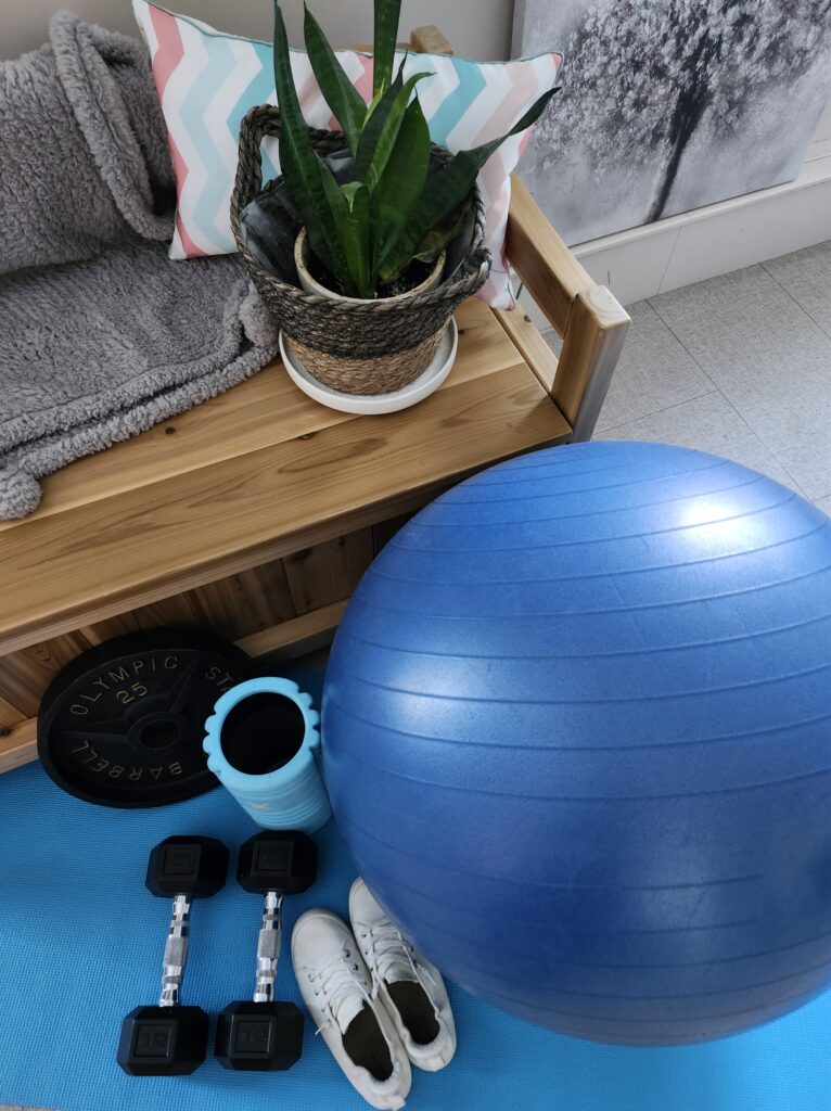 Corner of my home gym with a ball, weight plate, dumbbells and shoes ready to workout