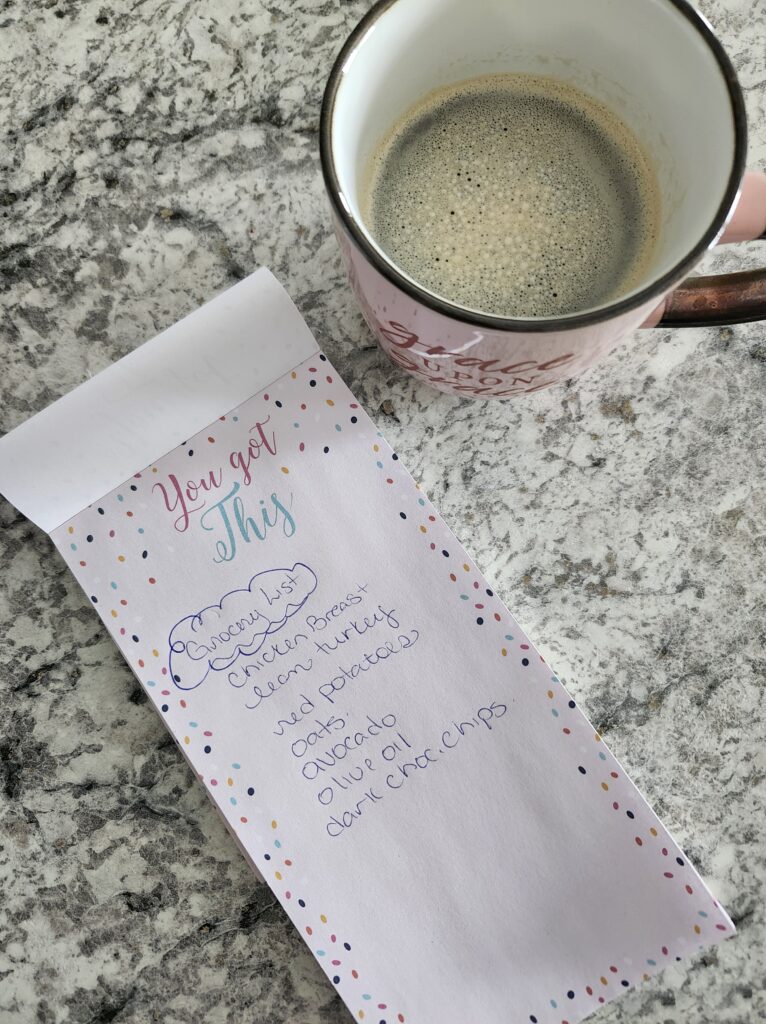 Creating grocery list for buying  gorceries on the counter with a cup of tea.