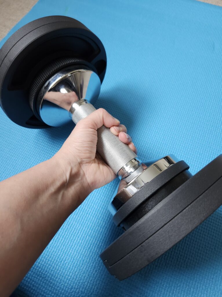 Hand gripping a adjustable dumbbell preparing for a workout