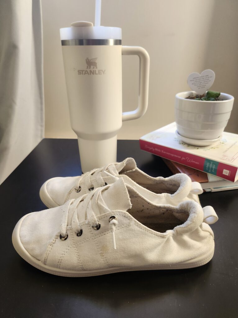 Shoes and water bottle on a table with books and a plant ready to go for a walk