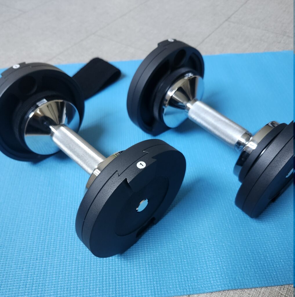 Adjustable dumbbells on a blue exercise mat – simple home gym setup for women starting strength training after 40